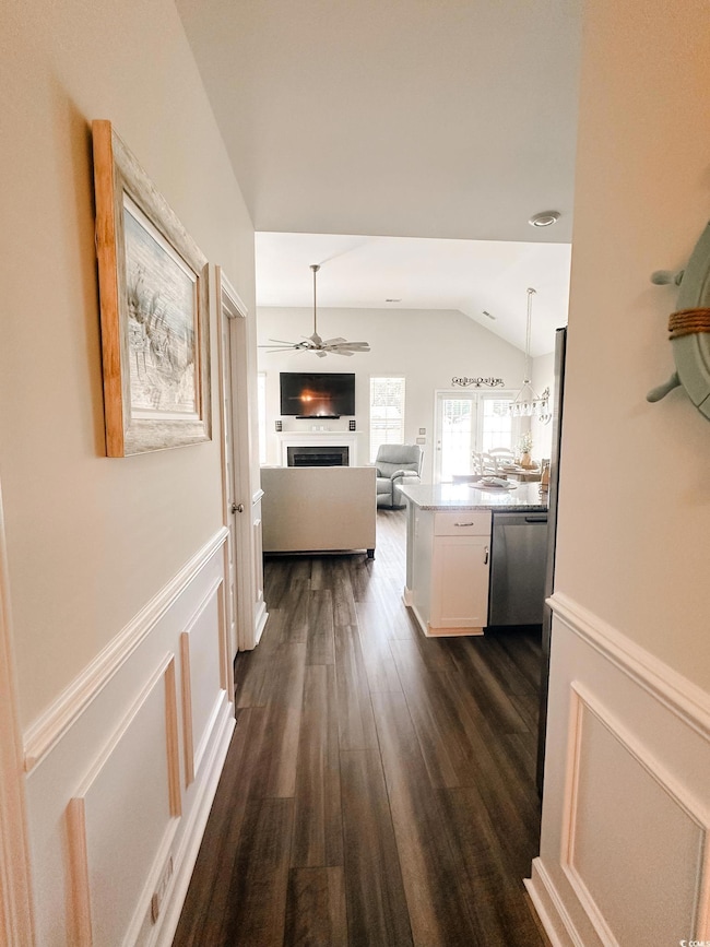 Hallway with vaulted ceiling and dark wood-type flooring