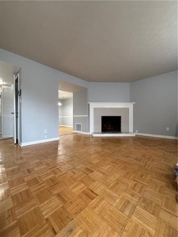 Unfurnished living room with a fireplace with raised hearth and baseboards