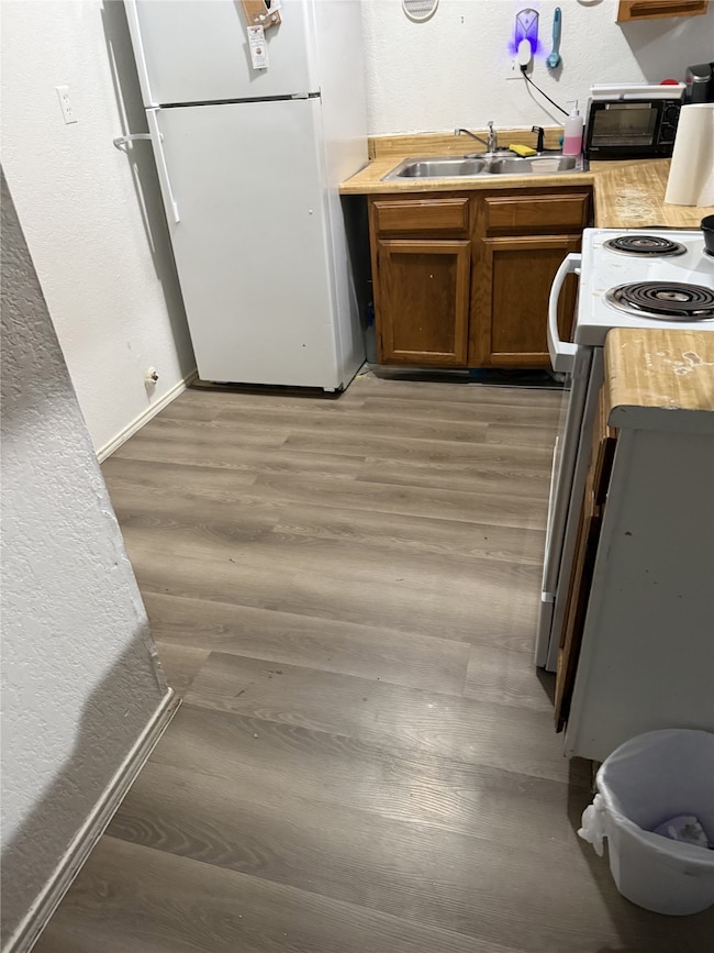 610A - Kitchen with a textured wall, white appliances, Light-wood style luxury plank flooring and oak cabinetry