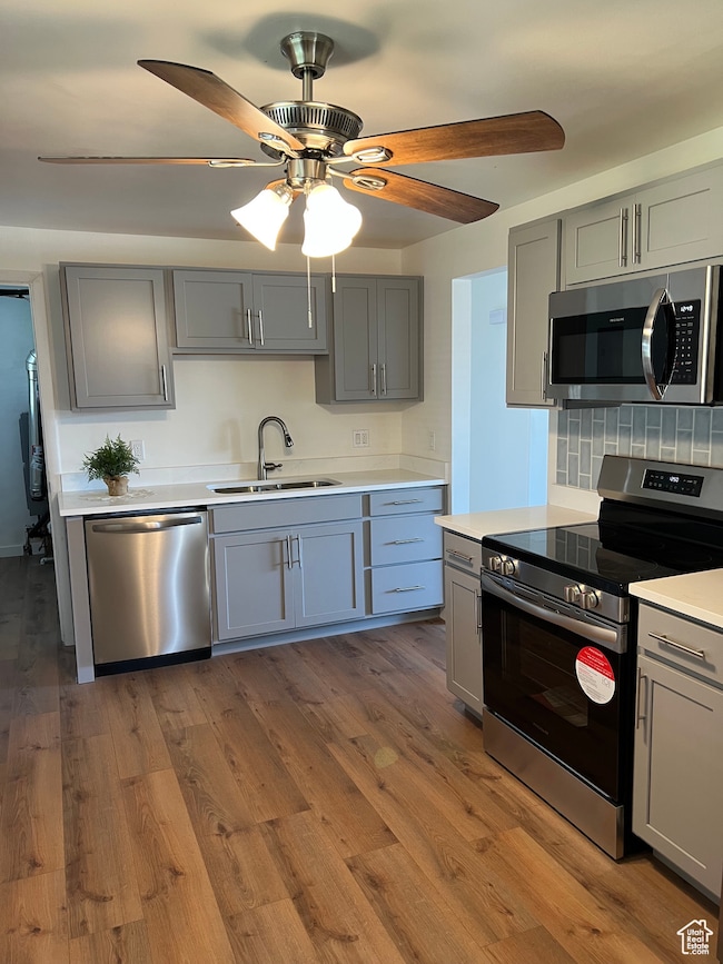 Kitchen featuring gray cabinetry, appliances with stainless steel finishes, backsplash, and ceiling fan