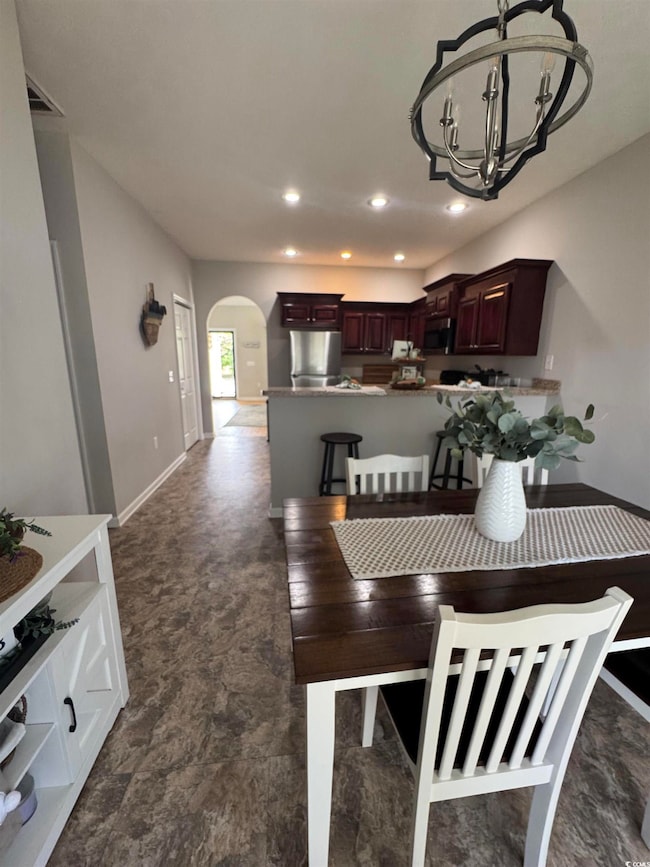 Dining room with an inviting chandelier, arched wa