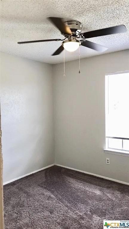 Unfurnished room featuring a ceiling fan, a textu
