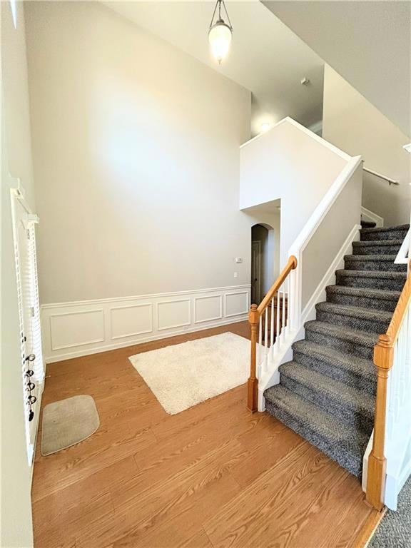 Stairway featuring wood finished floors, wainscoting, arched walkways, and a decorative wall