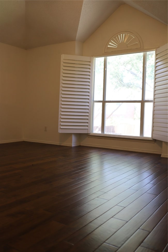 Unfurnished room with lofted ceiling and dark wood-style floors