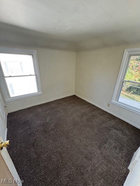 Unfurnished room featuring dark carpet and a textured ceiling