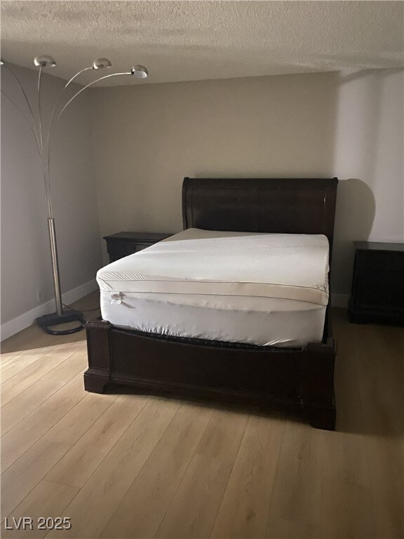 Bedroom with a textured ceiling and light wood-style flooring