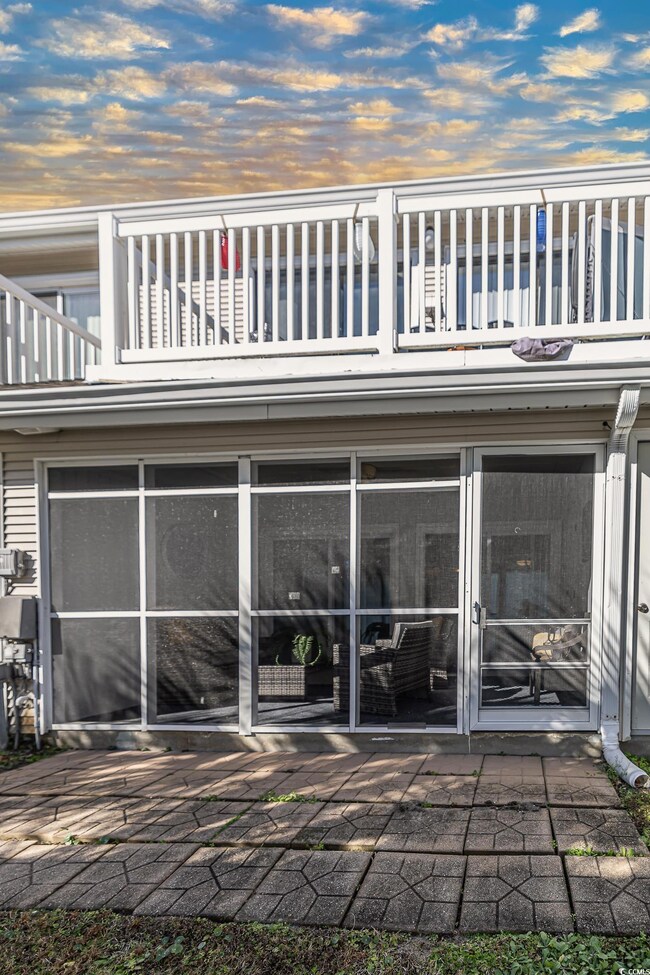 Back house at dusk with a sunroom, a balcony, and 