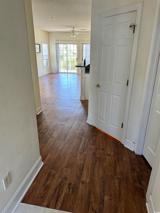 Corridor featuring a textured ceiling and hardwood
