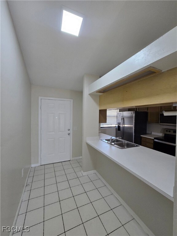 Kitchen featuring light countertops, a peninsula, appliances with stainless steel finishes, and light tile patterned flooring