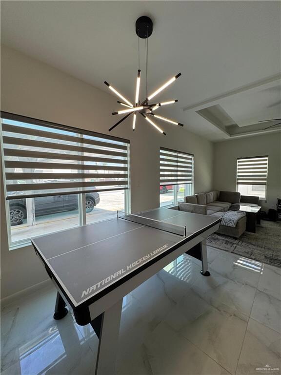 Game room with plenty of natural light, a chandelier, and marble finish flooring