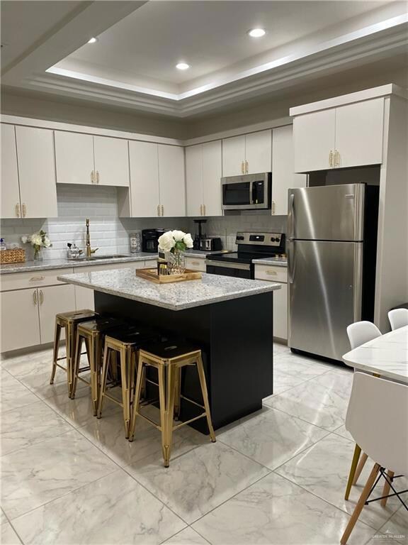 Kitchen with appliances with stainless steel finishes, backsplash, and white cabinetry