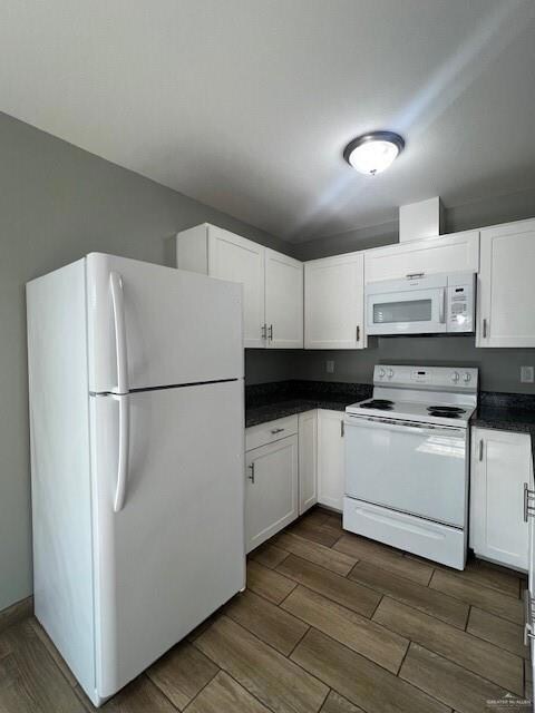Kitchen featuring white cabinets, wood-type flooring, fridge, and range