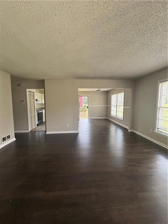 Unfurnished living room featuring a textured ceiling and dark wood-style floors