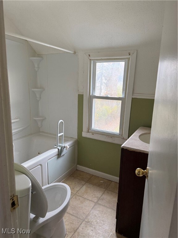 Bathroom featuring vanity, a combined bath / shower with jetted tub, a textured ceiling, and light tile patterned floors