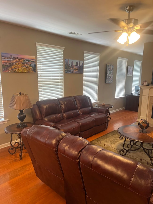 Living room featuring baseboards, light wood-style floors, and ceiling fan
