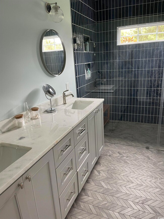 Full bath featuring double vanity, a tile shower, and plenty of natural light