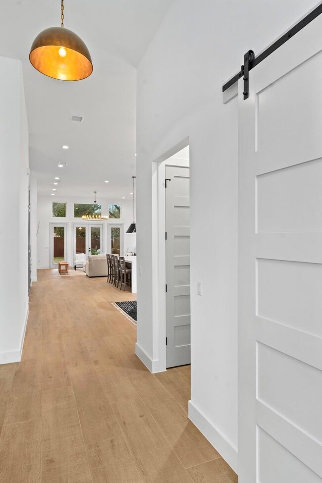 Corridor featuring a barn door, light wood-style 