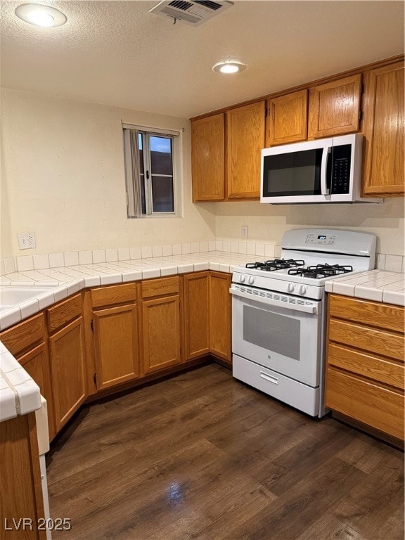 Kitchen with brown cabinetry, tile countertops, da