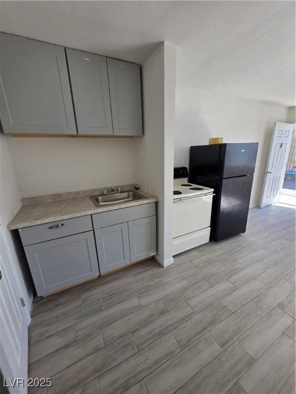 Kitchen featuring gray cabinets, stove, wood tiled floors, and light countertops