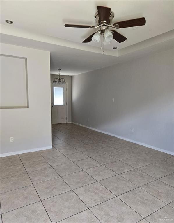 Spare room with ceiling fan, light tile patterned floors, a chandelier, and a tray ceiling