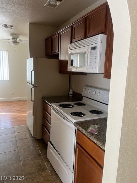 Kitchen with a ceiling fan, visible vents, a textured ceiling, and stove
