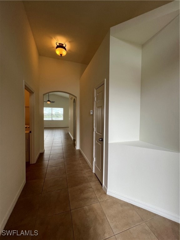 Hall featuring arched walkways and tile patterned flooring