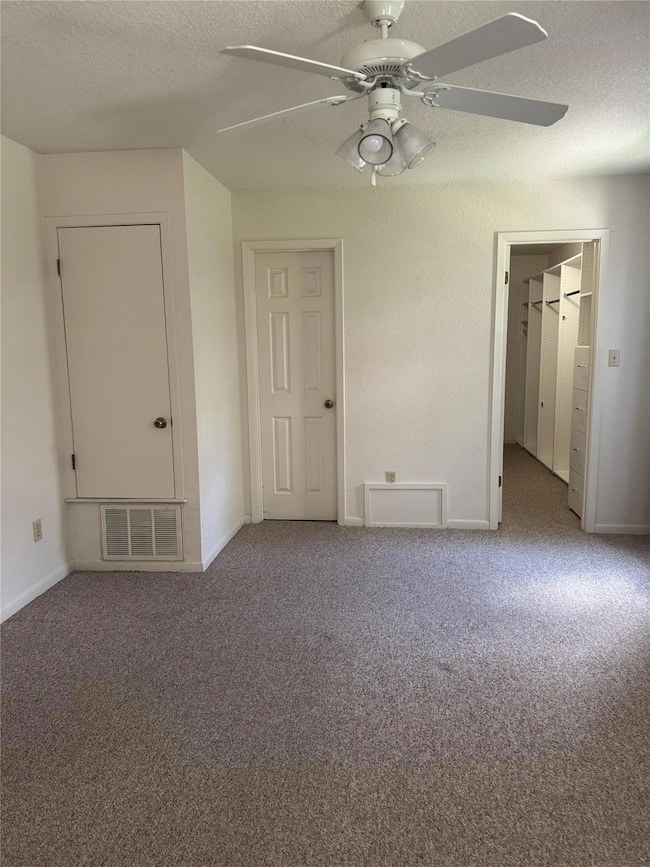 Empty room with a ceiling fan, carpet flooring, a