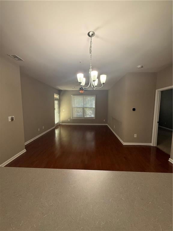 Unfurnished room with a chandelier and dark wood-style floors