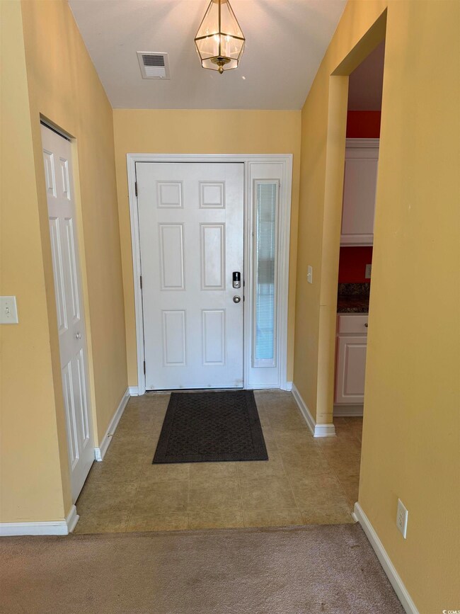 Foyer featuring light tile patterned flooring and light colored carpet