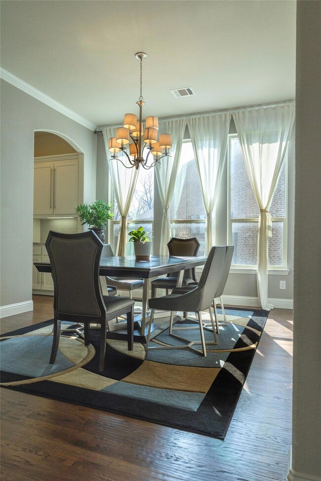 Dining area with an inviting chandelier, wood-type flooring, and ornamental molding