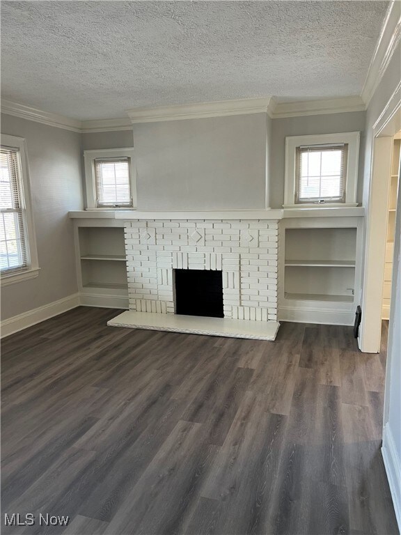 Unfurnished living room featuring a fireplace, crown molding, and dark wood-style floors