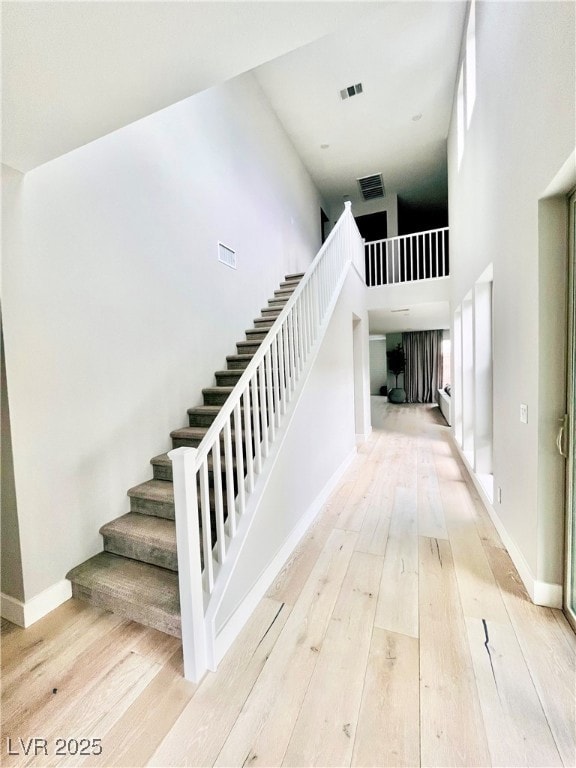 Stairs with a high ceiling, wood-type flooring, an