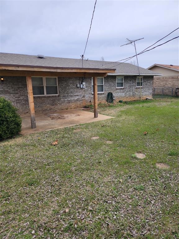 Rear view of house with a yard, a patio, brick sid