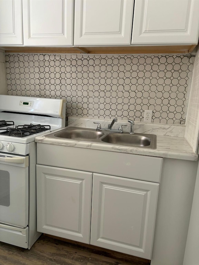 Kitchen featuring white gas range, white cabinets