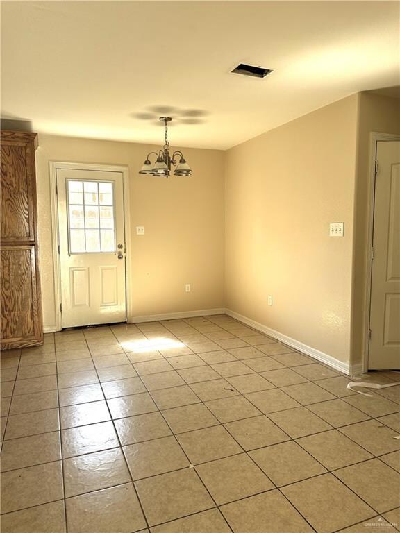 Unfurnished dining area with light tile patterned floors and a chandelier