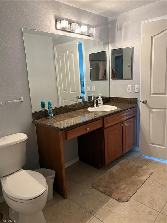 Bathroom with a textured wall, vanity, and light tile patterned floors