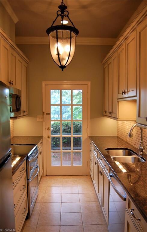 Galley Kitchen is enhanced with Stainless Appliances, Granite Counters, Tile Back Splash, Double Sinks and Custom Cabinetry
