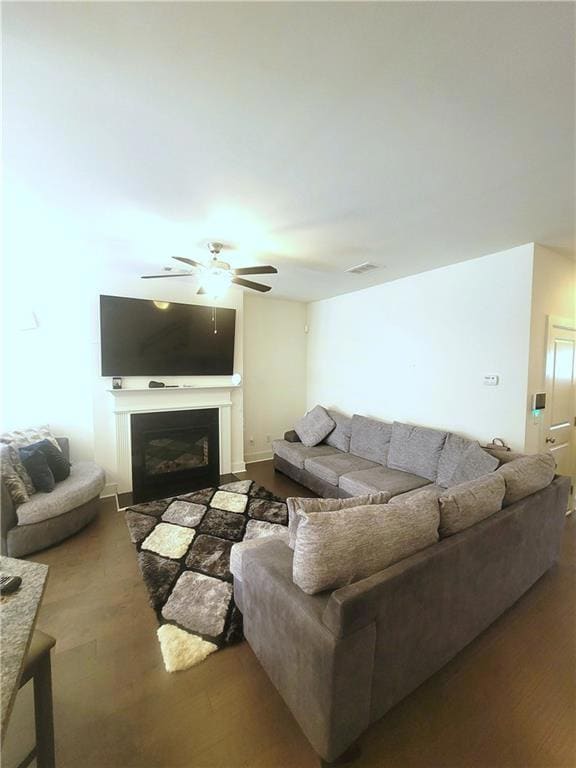 Living room with ceiling fan, wood finished floors, and a glass covered fireplace