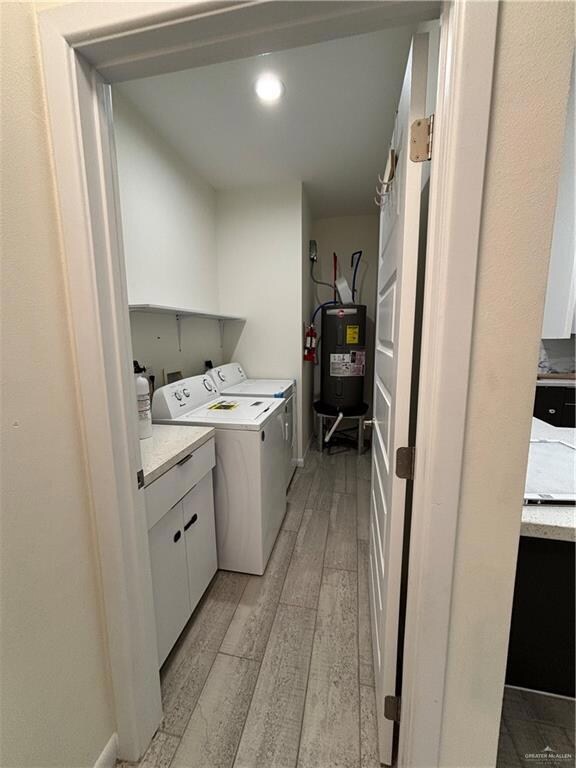 Washroom with light wood-style flooring, water heater, and separate washer and dryer