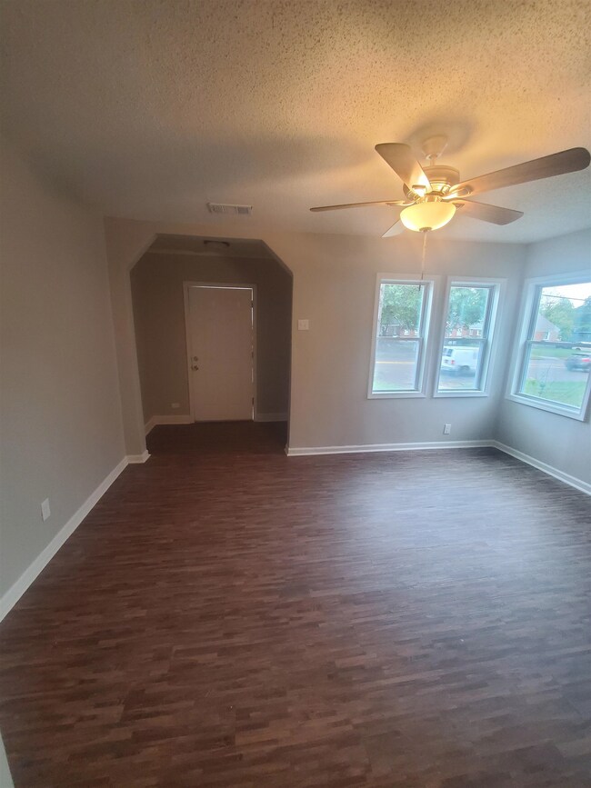 Living room with ceiling fan, a textured ceiling, 