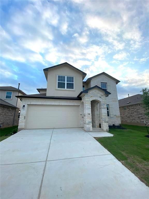View of front of home featuring stone siding, driveway, a garage, a front lawn, and stucco siding