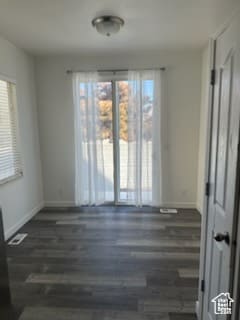 Unfurnished room featuring baseboards and dark wood-type flooring