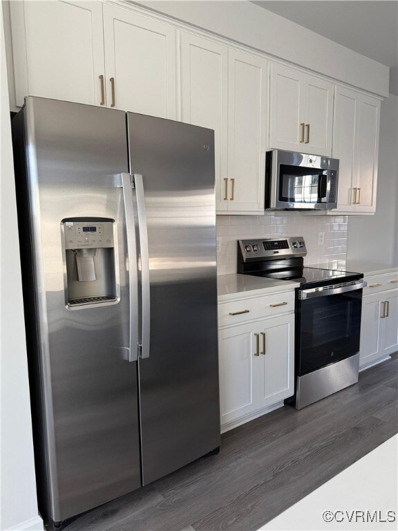 Kitchen featuring dark hardwood / wood-style flooring, white cabinetry, and appliances with stainless steel finishes