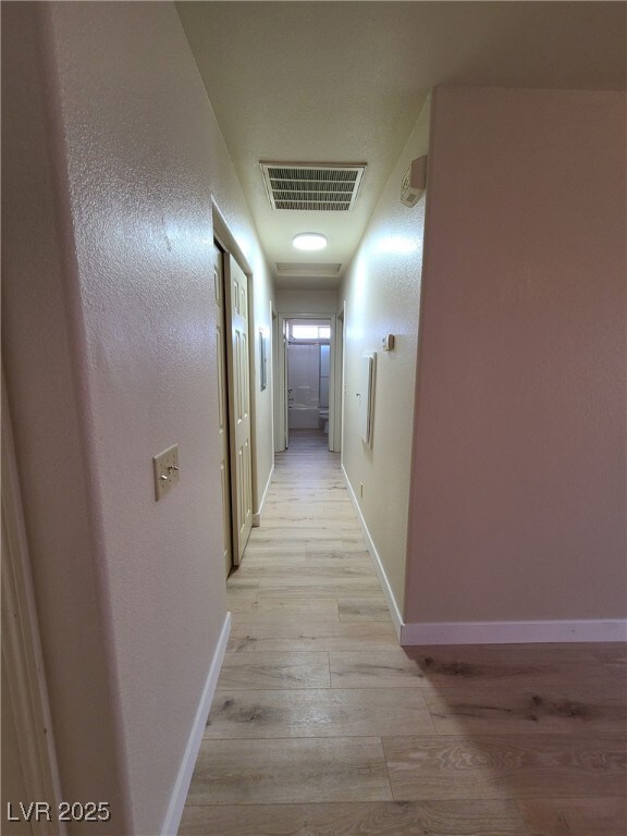 Hall with light wood-style floors and baseboards