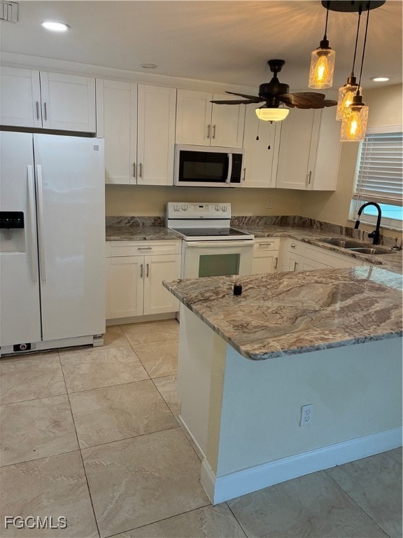 Kitchen with fridge, light stone counters, white cabinetry, stainless steel microwave, and decorative light fixtures