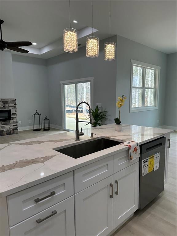 Kitchen with a sink, a ceiling fan, white cabinetr