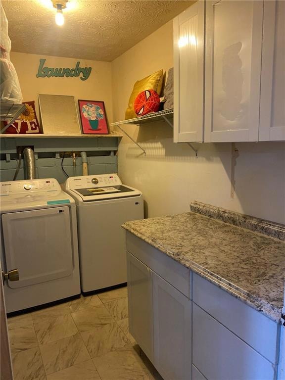 Washroom featuring independent washer and dryer, cabinet space, a textured ceiling, and light marble finish flooring