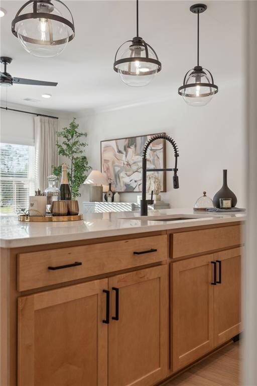 Bar area featuring decorative light fixtures, light wood finished floors, and a sink