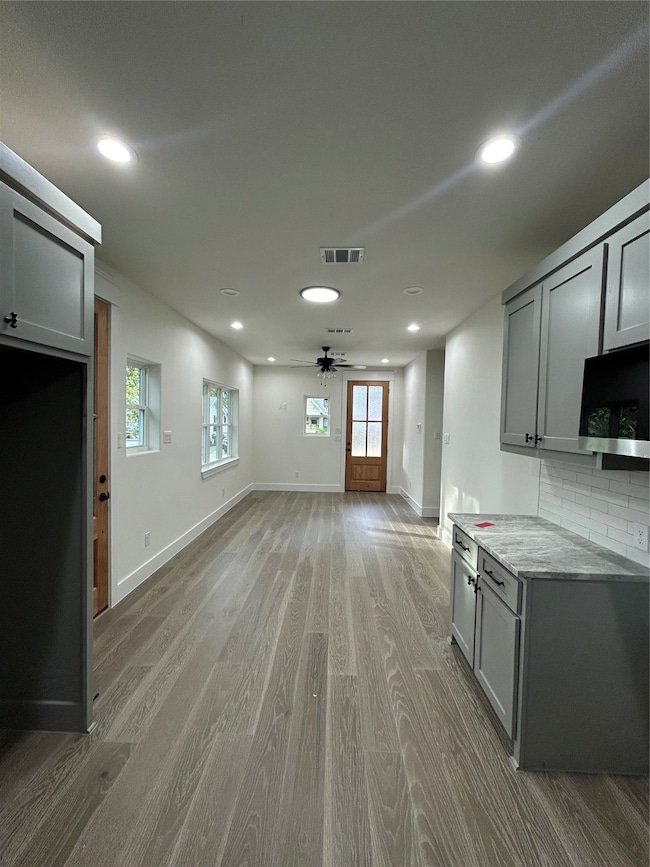 Kitchen with gray cabinets, wood finished floors, recessed lighting, tasteful backsplash, and ceiling fan