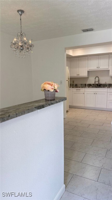 Kitchen with a sink, a textured ceiling, a chandel